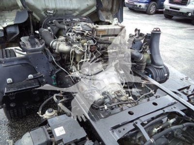 Isuzu NPR XD truck engine bay exposed with components and hoses; view shows engine mounting area and surrounding frame.