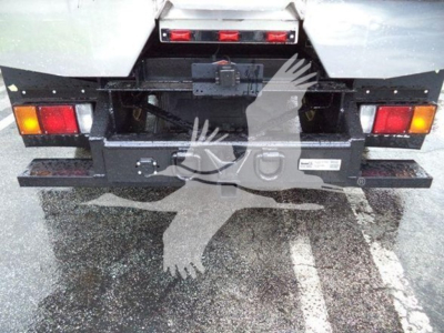 Isuzu NPR XD dump truck rear showing bumper with taillights and hitch; metal plates and warning labels present.