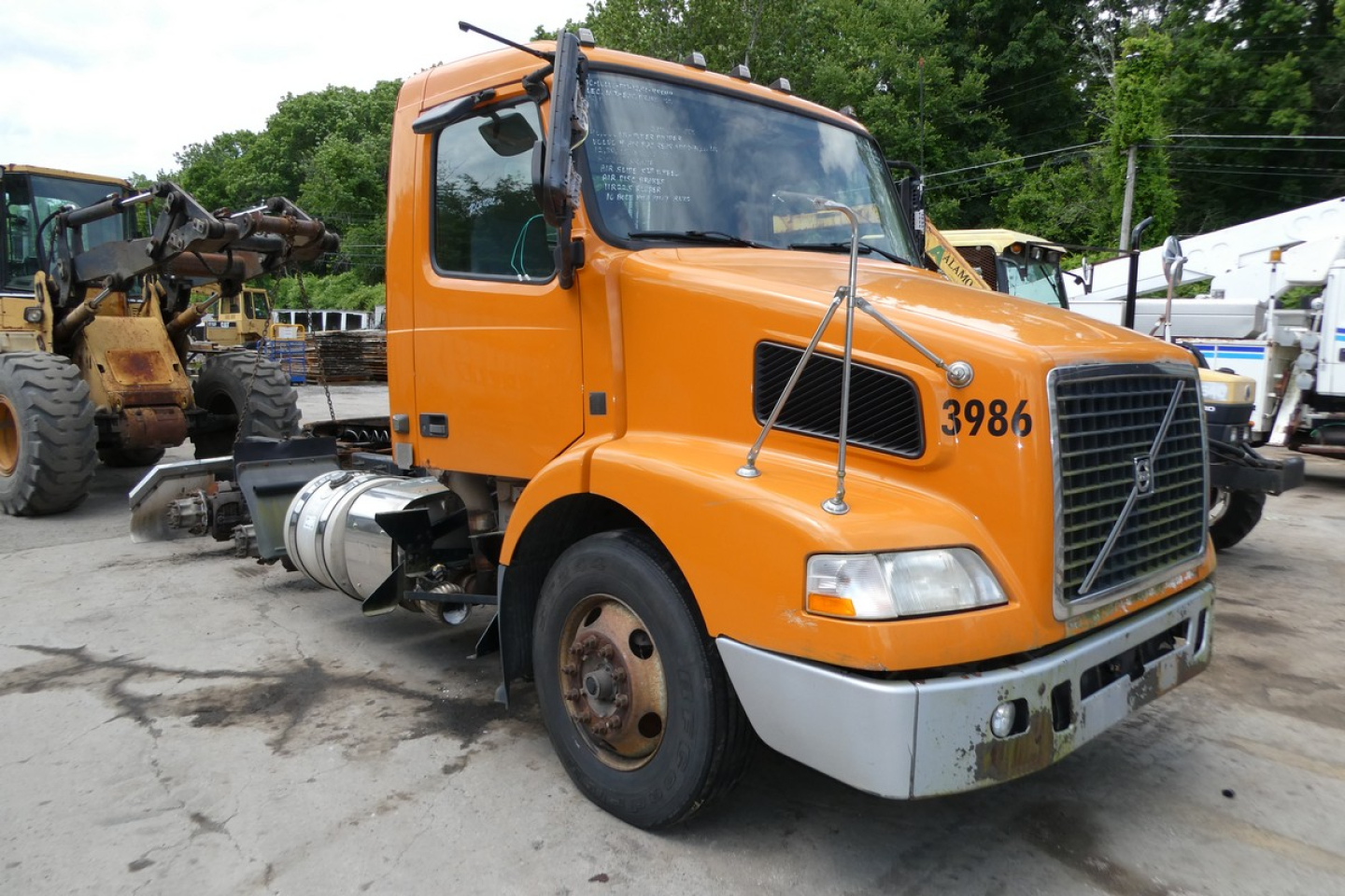 Volvo VNM64T conventional daycab truck front view showing orange cab and chassis with large grille and dual mirrors.