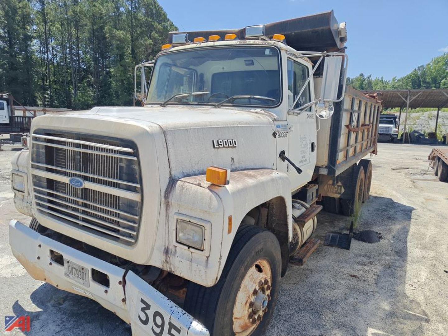 Ford LT9000 dump truck with open-box bed, cab front grille, L9000 badge on fender, headlights, orange marker lights, and dirt/grime on white paint.