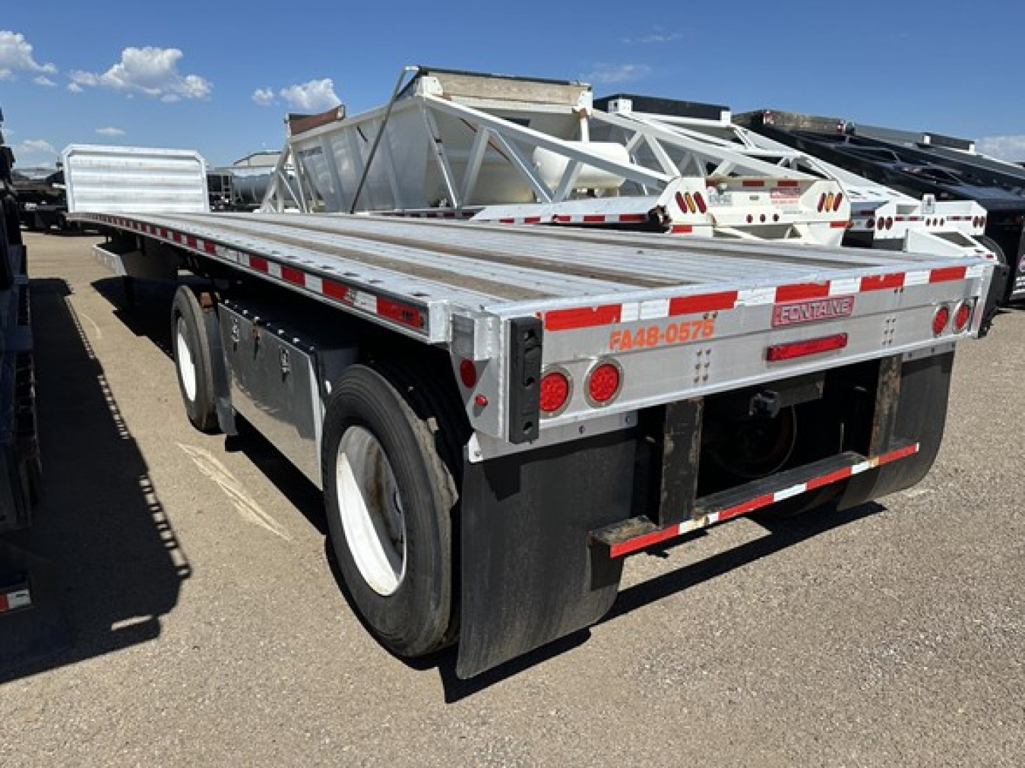 Flatbed trailer rear view showing Fontaine brand logo, dual rear ramps, load distribution, and reflective tape.