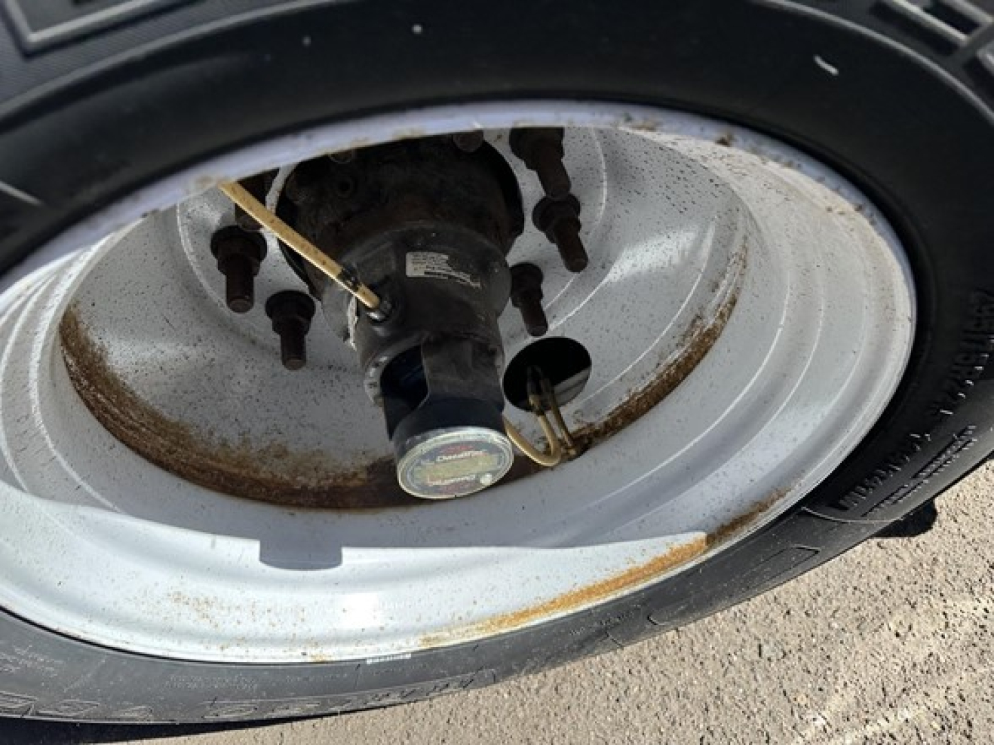 Trailer wheel hub and tire close-up showing steel rim with rust stains, lug nuts, and hub cap on a Fontaine trailer.