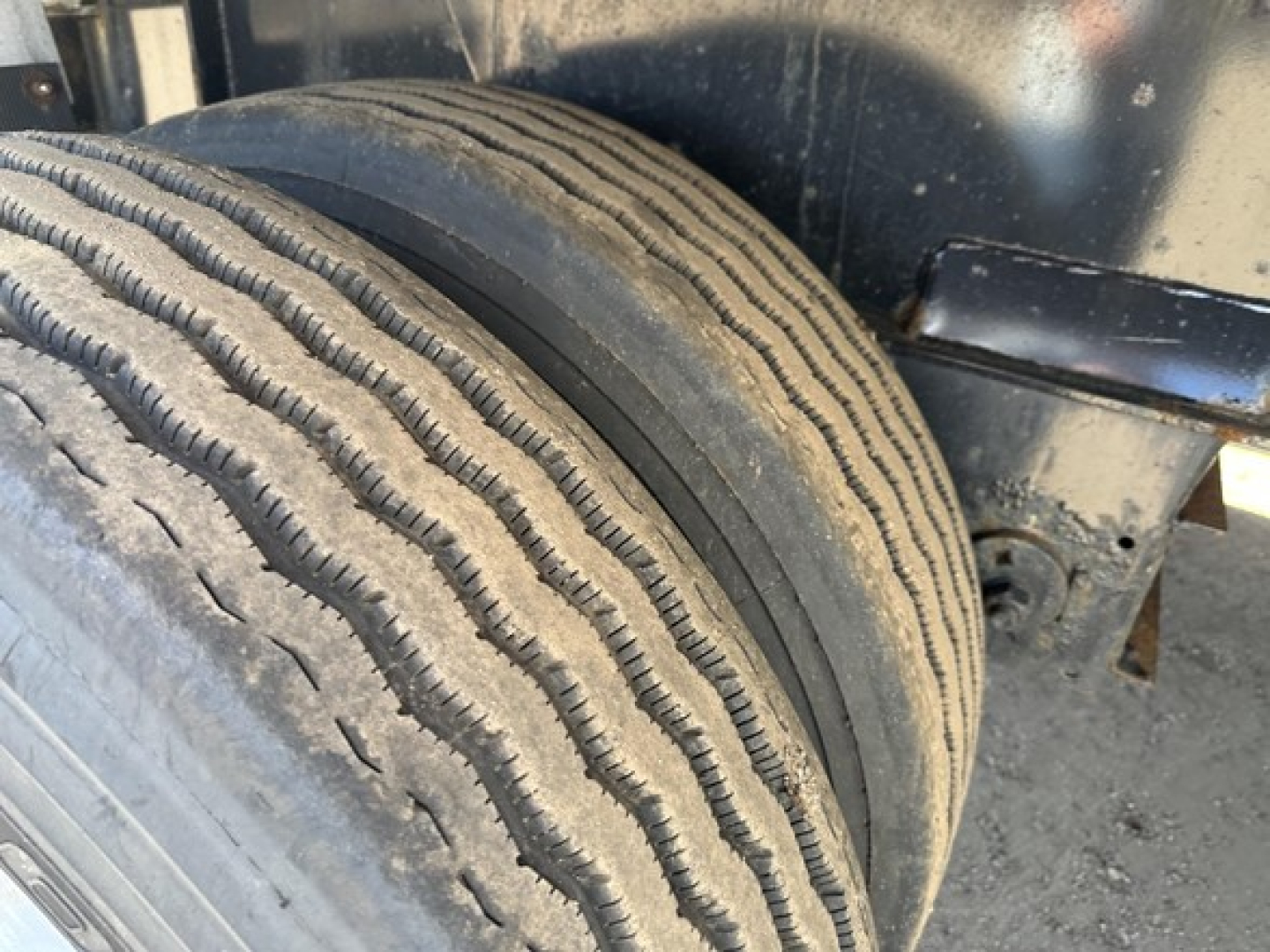 Flatbed trailer tire close-up showing dual tires and wheel well undercarriage.