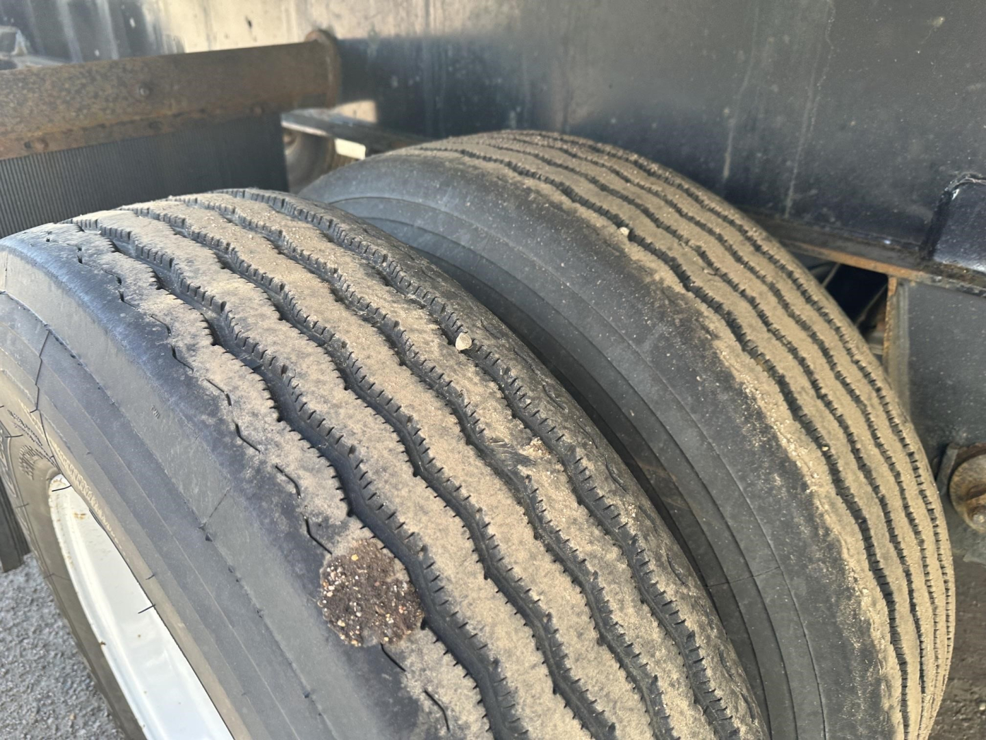 Trailer axle with dual wheels showing tread wear and in-service condition.