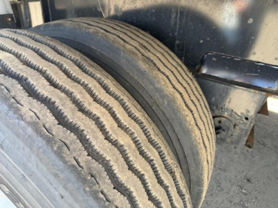 Flatbed trailer tire close-up showing dual tires and wheel well undercarriage.