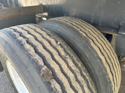Trailer wheel assembly showing dual tires with visible tread grooves and dirt on the rims.