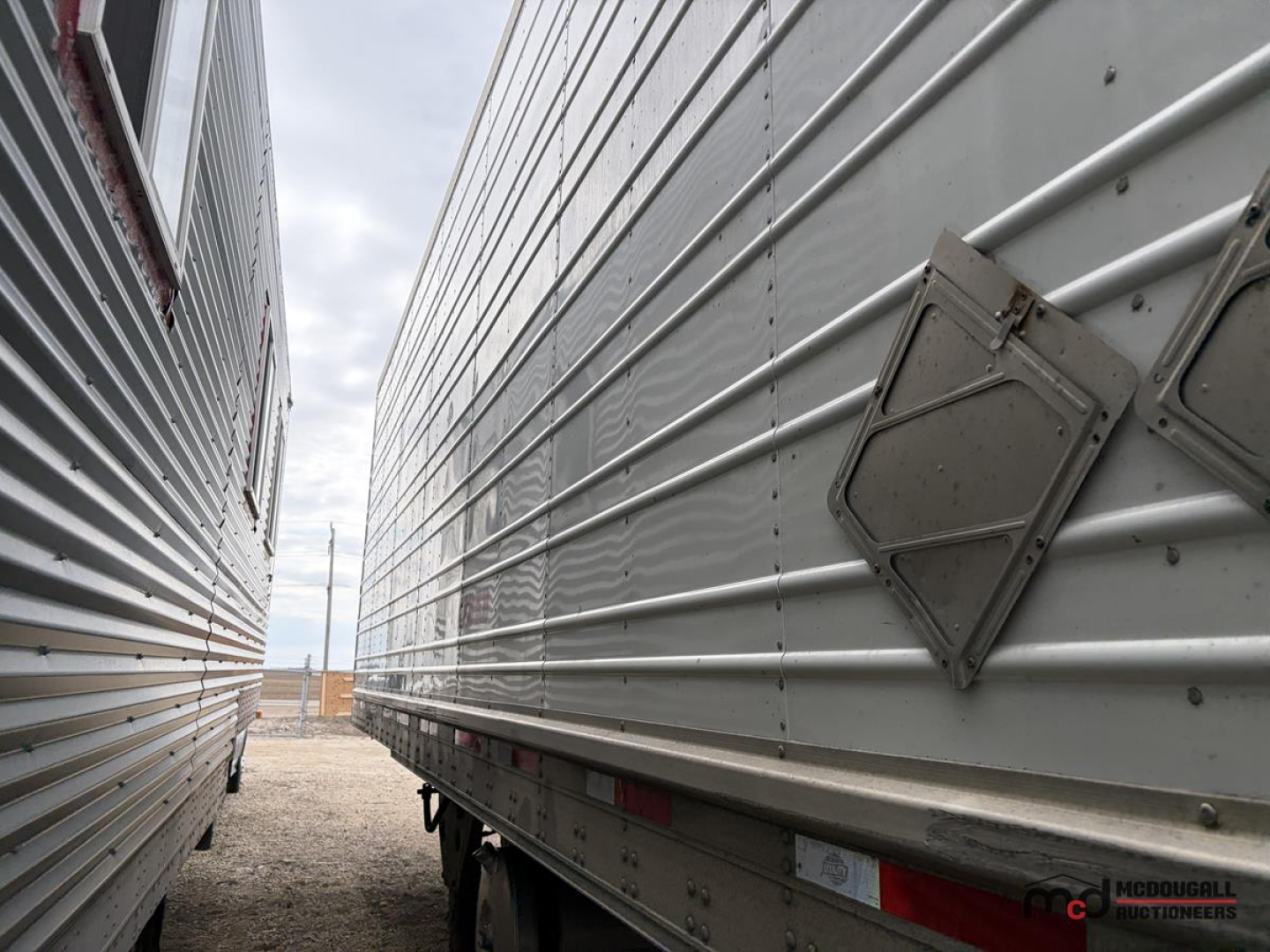 Trailer side view showing stainless steel corrugated wall and rear corner with diamond access hatch, 53' reefer trailer
