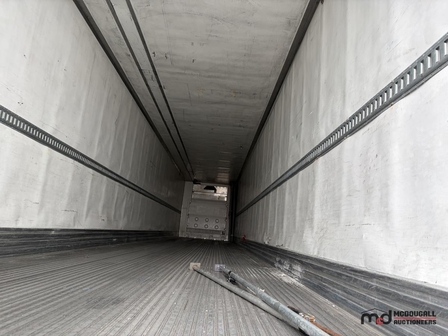 Trailer interior showing empty 53' refrigerated trailer with metal flooring and side walls, rear doors closed, visible rails along walls.