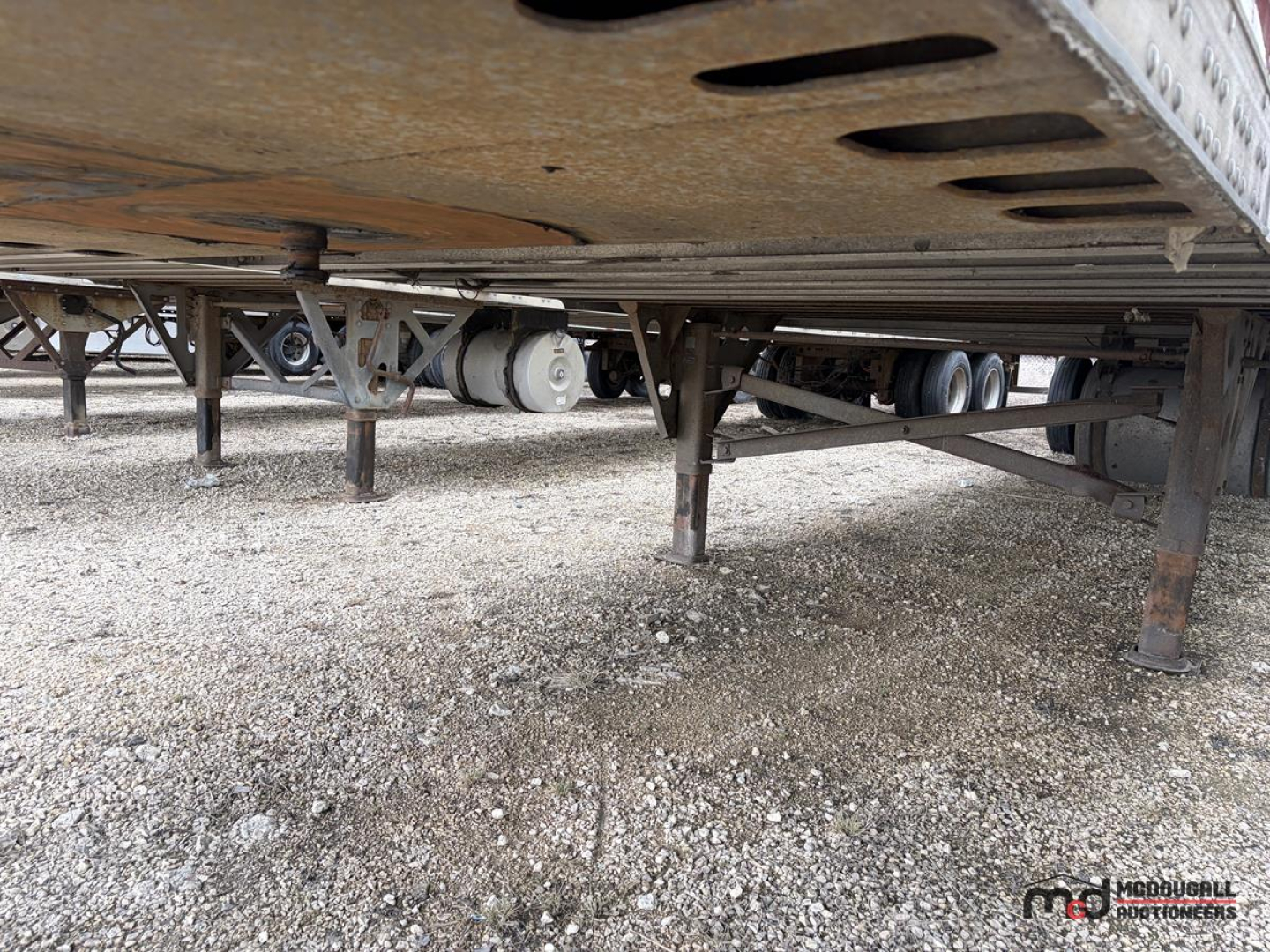 Semi trailer underside showing landing gear and suspension with tank and piping visible under a 53' reefer trailer.