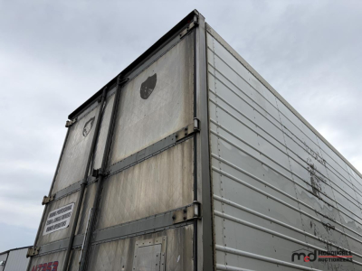 Trailer rear/side view of a 53' utility tri-axle reefer trailer showing metal siding, hinge doors, and wear marks.