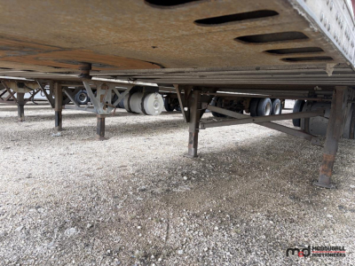 Semi trailer underside showing landing gear and suspension with tank and piping visible under a 53' reefer trailer.