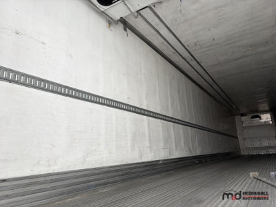 Trailer interior showing long white refrigerated trailer walls and floor with ceiling rails.