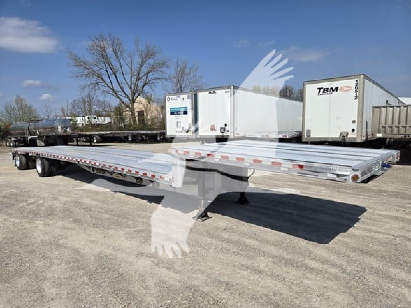 Trailer deck showing a 53-foot drop deck trailer with tandem axles and refrigeration unit in background.