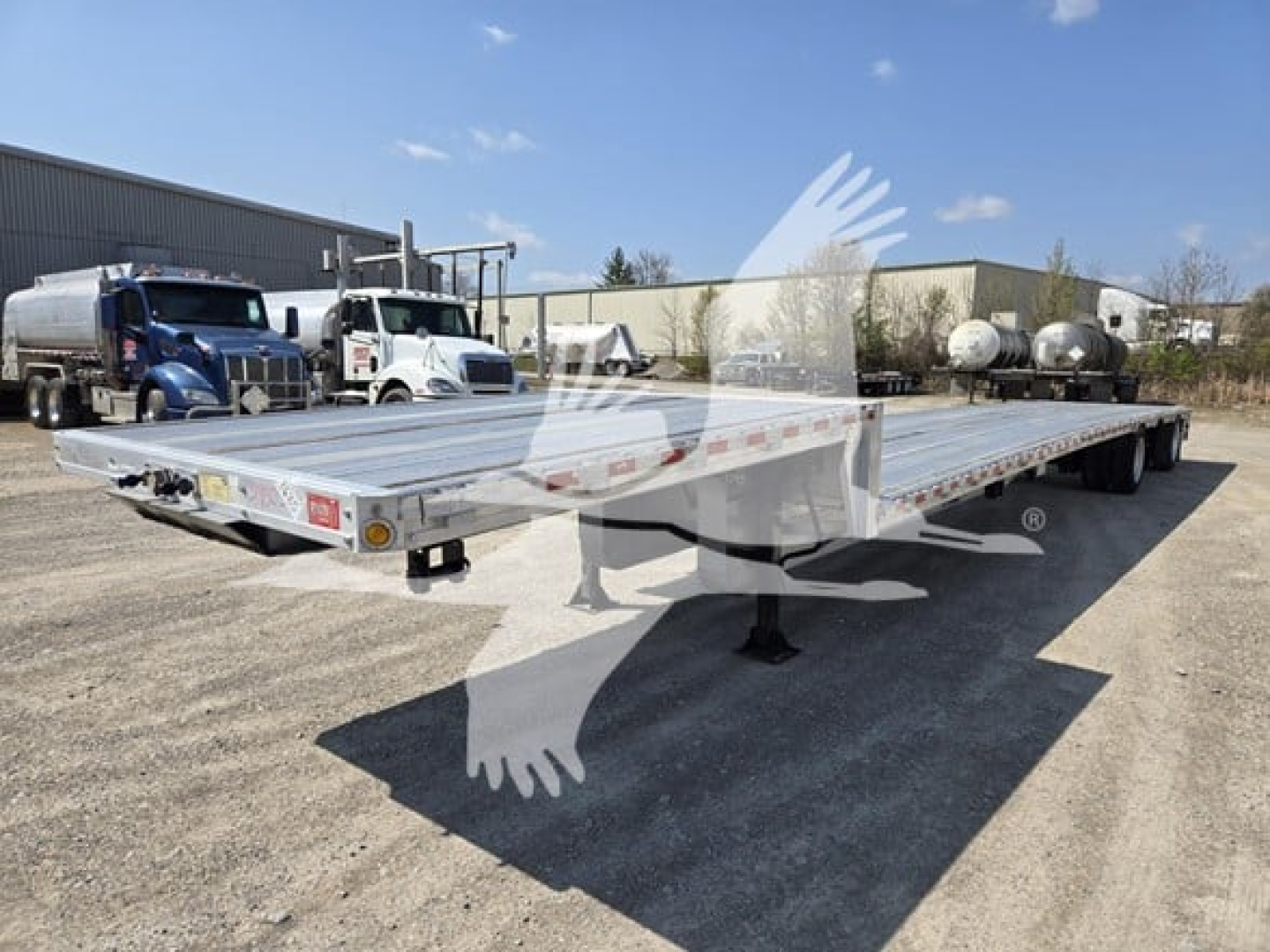 Trailer with flatbed deck showing drop deck design and tandem axles, aluminum surface, and support legs in a used condition.