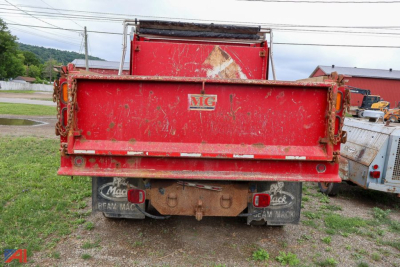 Rear view of a red GMC TopKick dump truck showing truck bed and plow mounts with mud flaps and tail lights.