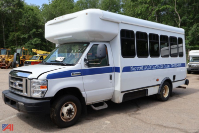 Ford E-350 shuttle bus with wheelchair lift, white body, blue stripe, side windows, front grille and wheel, used condition.