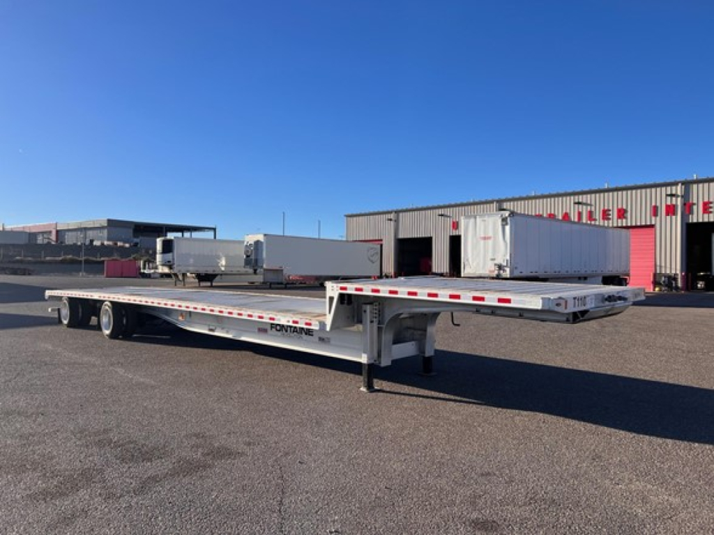 2020 Fontaine Revolution drop deck trailer in a parking lot, showing a long aluminum flatbed with sunken wheel wells and 'Fontaine' branding on the side.