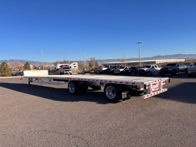 Flatbed trailer in a parking lot with clear sky and distant mountains, Fontaine Revolution 2020, drop deck trailer, stock UE11319.