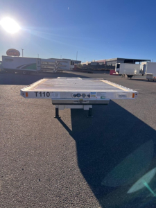 Trailer flatbed with T110 marking on rear, Fontaine Revolution drop deck trailer in outdoor lot.