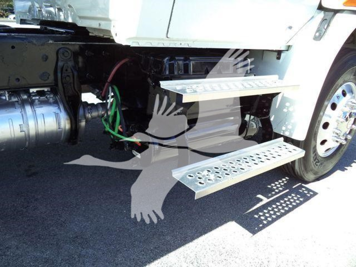 Truck side step area showing metal running boards and undercarriage with hoses and driveline components visible.
