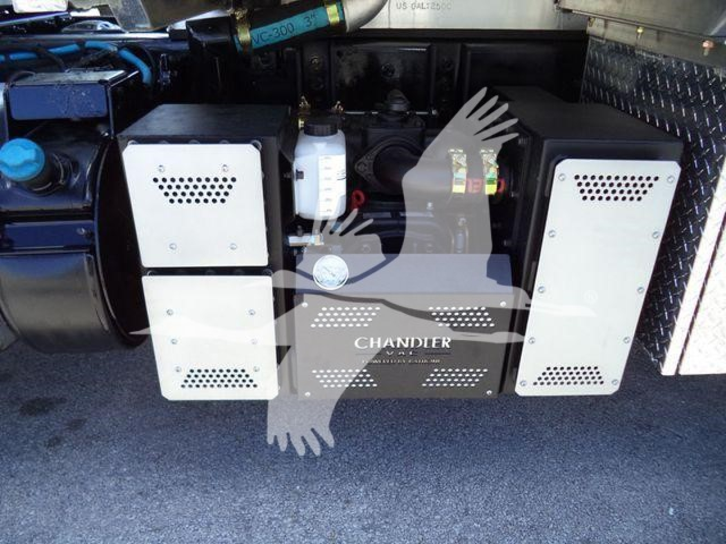 Rear view of a vacuum tank International MV truck showing twin metal boxes with perforations and a central control panel labeled CHANDLER.