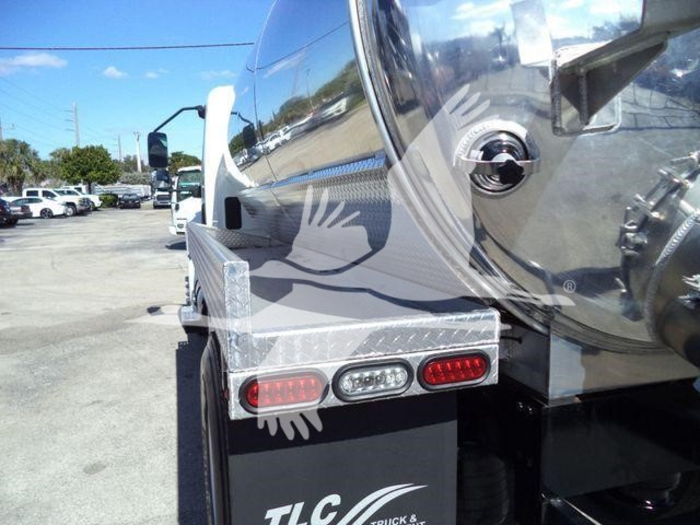 Trucked vacuum tank rear corner showing aluminum toolbox, rear lights, and reflective surface of tank.