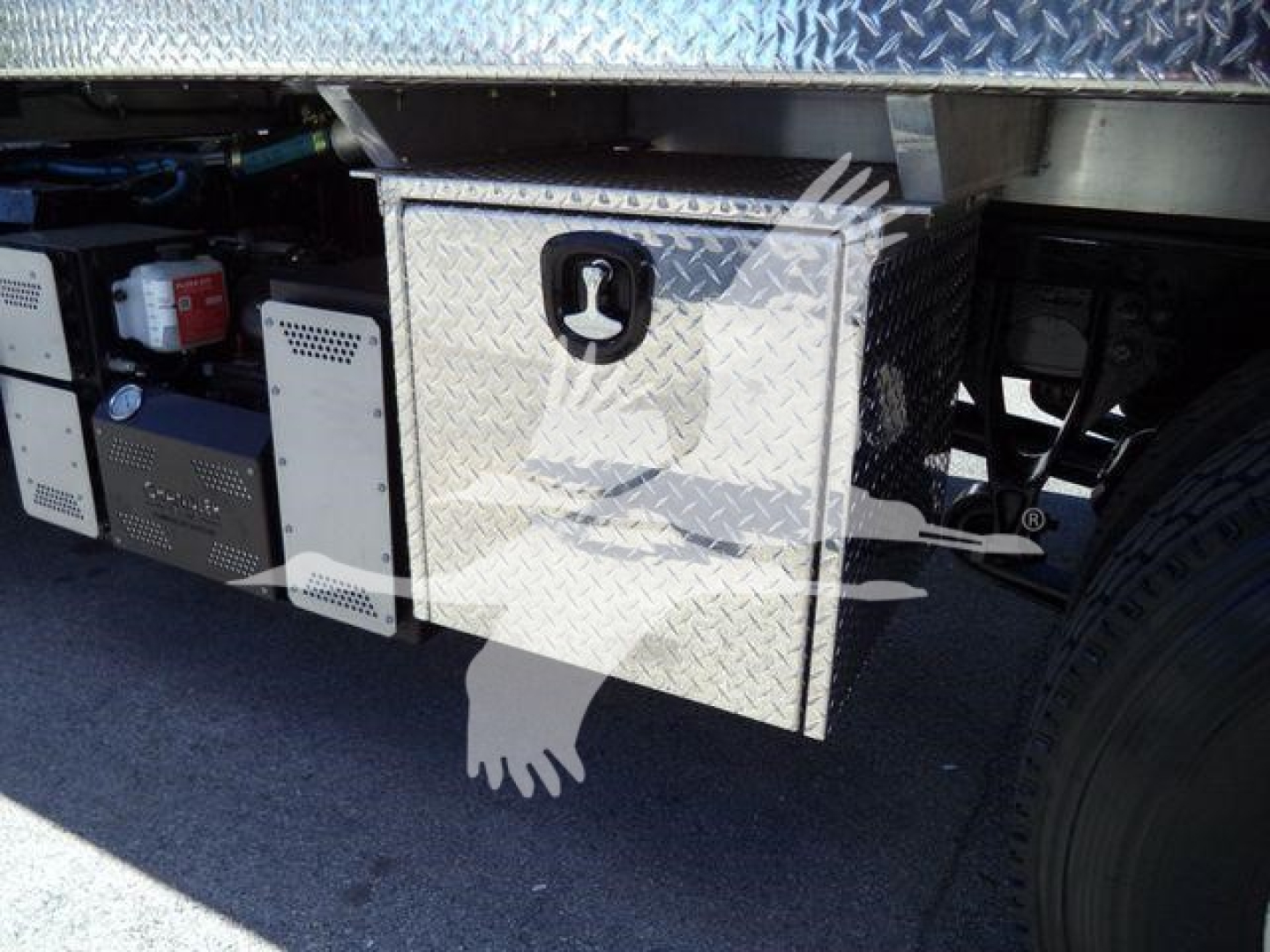 Undertruck storage box and equipment components on a 2021 International MV vacuum tank truck showing diamond plate toolbox with latch and adjacent engine area