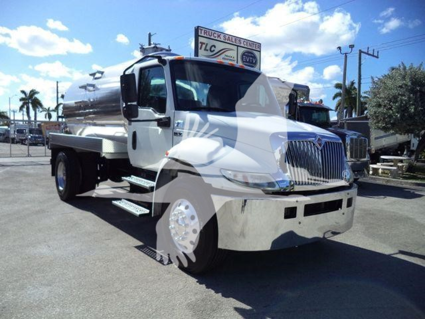 International MV vacuum tank truck shows front and left side view with chrome bumper, silver cylindrical tank, and vacuum equipment.