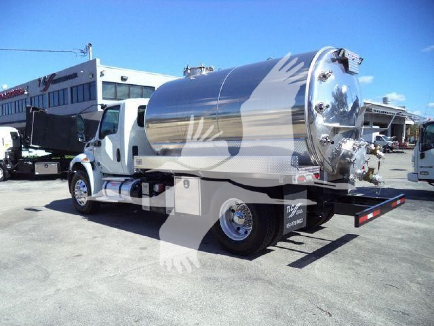 International MV vacuum tank truck with polished stainless tank, side view, rear discharge, chrome accents, dual rear wheels, flat rear platform.