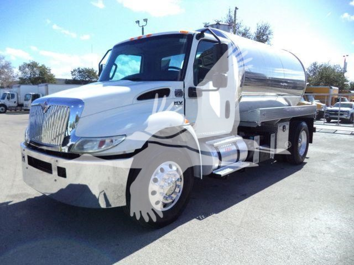International MV vacuum tank truck with white cab and polished stainless cylindrical tank, front grille, dual rear wheels, side step, and fuel tank visible.