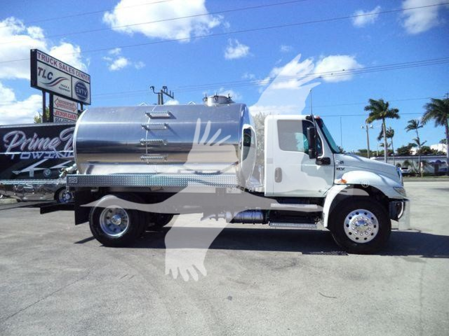 International MV vacuum tank truck side view showing polished stainless steel cylindrical tank and white cab.