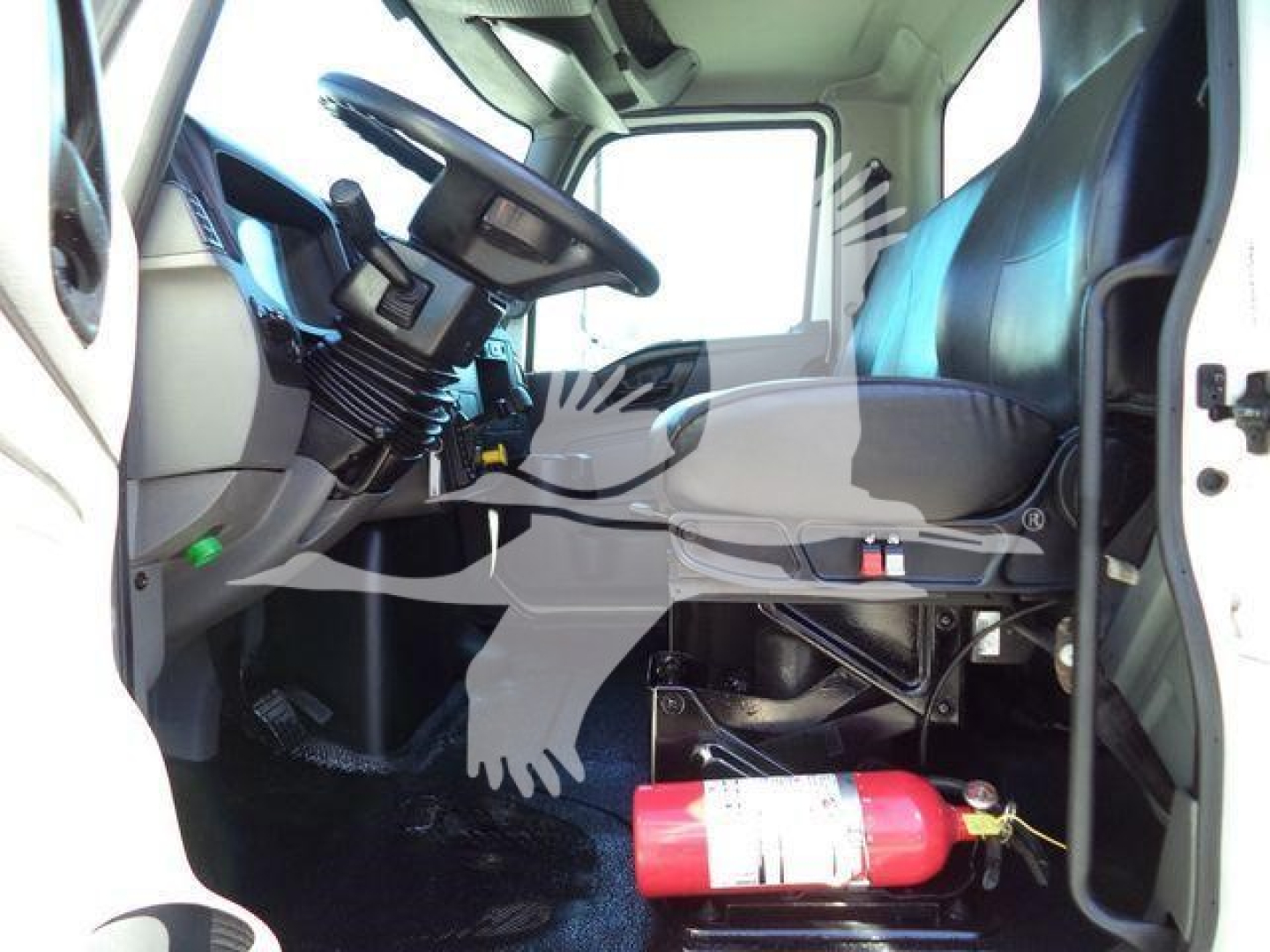 Interior of a 2021 International MV vacuum tanker truck cab showing steering wheel, seat, and a red fire extinguisher mounted beside the driver.