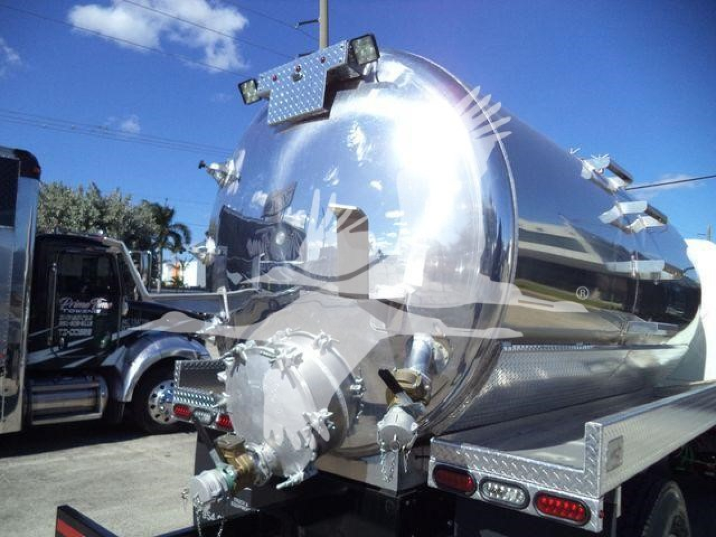 Volatile stainless steel vacuum tank truck with rear shutoff and mount brackets, chrome finish, and dual rear lights visible.