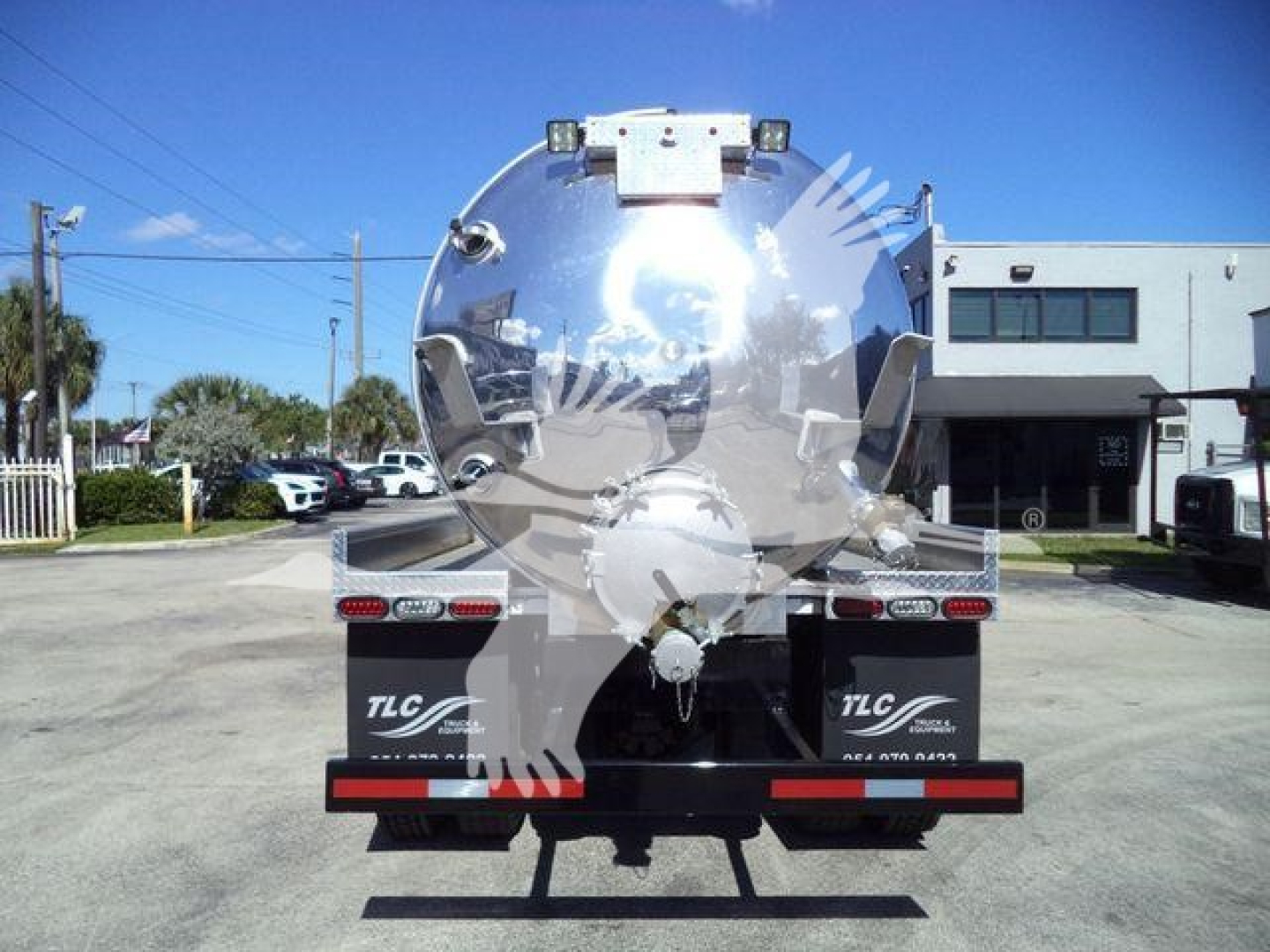 Vacuum tank truck rear view showing circular stainless tank, taillights, and bumper with TLC branding.