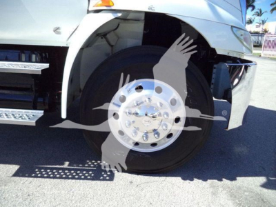Truck front wheel showing large aluminum hub with multiple lug nuts and partial front fender; no visible text readable on components.