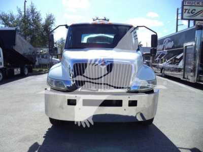 Truck front view showing International MV vacuum tank with chrome grille, large bumper, and daylight. Visible text on side banners: none legible.
