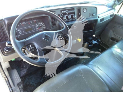 Dashboard and steering wheel of a 2021 International MV vacuum tank truck interior; visible instruments, steering wheel with logo, center console, pedals, and seats.