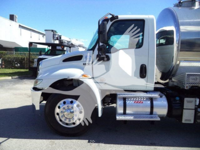 International MV vacuum tank truck side view showing front wheel, chrome fuel tank, and step with diamond plate.