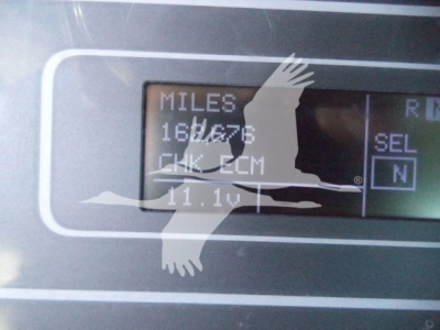 Digital/analog display on a vacuum tank truck showing mileage: MILES 180?76, CHK FCM, 11.1V, SEL N. Part of a display panel with a bird watermark.