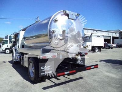 Tank truck rear view showing polished stainless steel vacuum tank with rear bumper and taillights; port holes and ladder rungs on top.