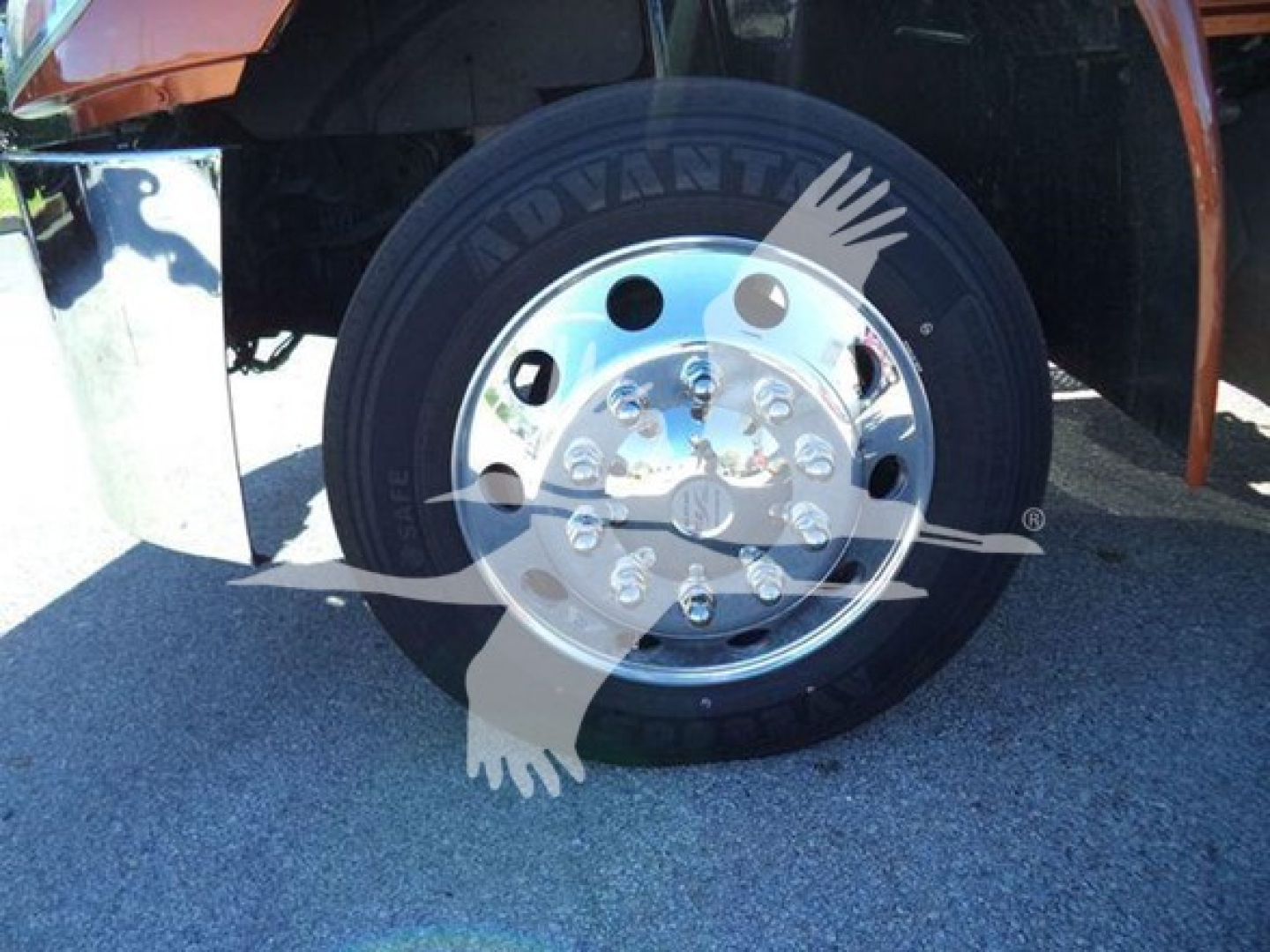 Truck wheel and chrome hub showing tire branding and chrome rim with lug nuts, part of International Durastar 4300 rollback.