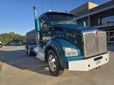 Kenworth T880 daytime cab front-left angle showing teal exterior, large chrome grille, fuel tanks, dual exhausts, and white front bumper.