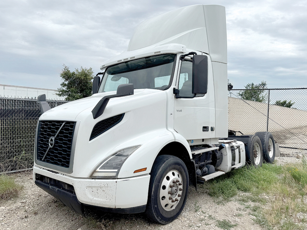 Truck side view showing 2020 Volvo VNR 300 daycab with white cab, large sleeper, black grille, and dual rear axles.