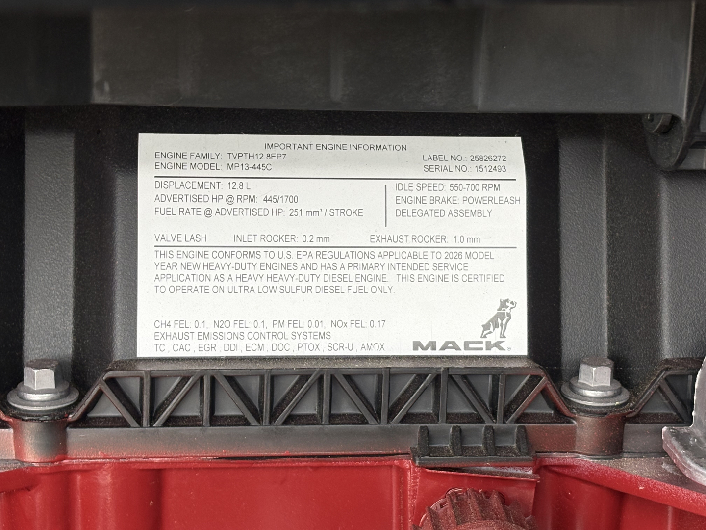 Engine label plate with engine family and model. Text includes engine model MP13-465E, displacement 12.8L, idle speed 500-700 RPM, power delete, etc.VIN area and Mack logo.