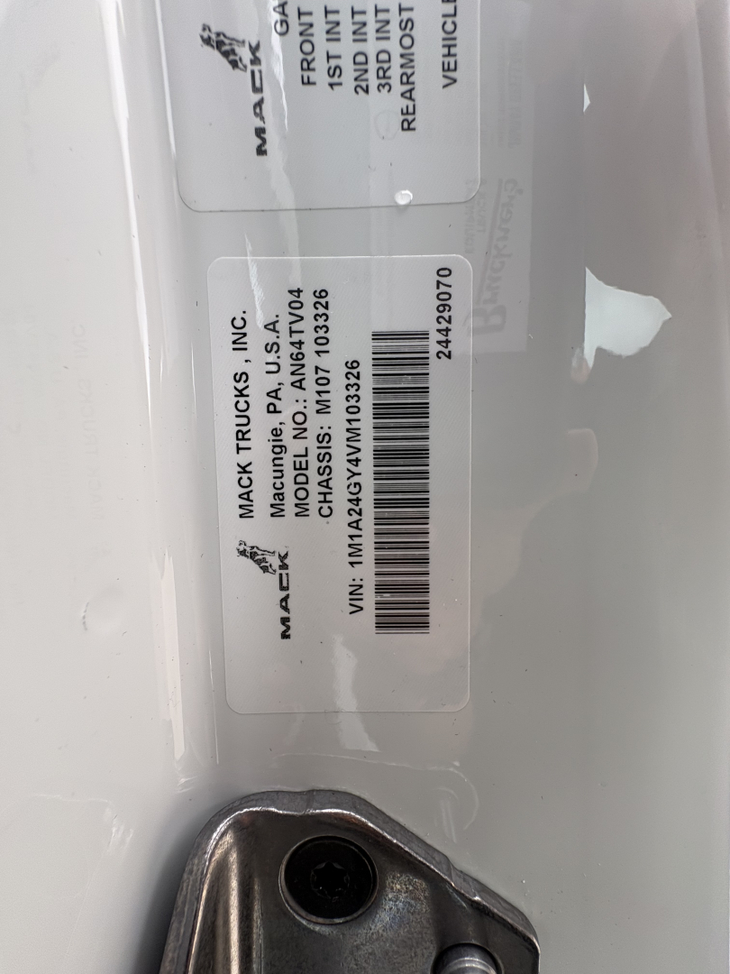 Mack label on truck showing VIN 1M1A24GY2VM103325 and stock number 72303 for a new Mack AN64T conventional daycab.