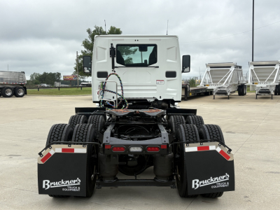 Tractor truck rear view showing dual rear axles, mudflaps with Bruckner logo, and white cab in background.