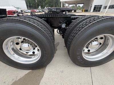 Dual rear truck wheels and fifth-wheel area of a Mack AN64T tractor showing dual tires, chrome hubs, and suspension components.