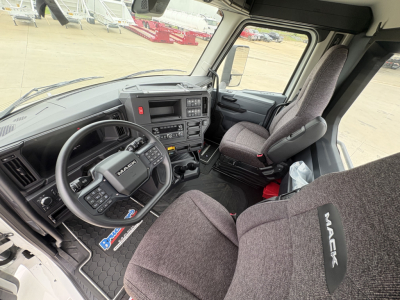 Mack AN64T truck cab interior showing steering wheel with Mack logo, dash controls, center console, and gray fabric seats.