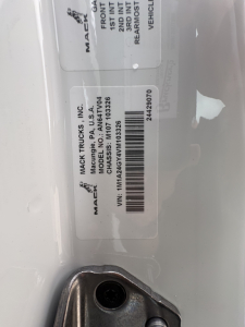 Mack label on truck showing VIN 1M1A24GY2VM103325 and stock number 72303 for a new Mack AN64T conventional daycab.