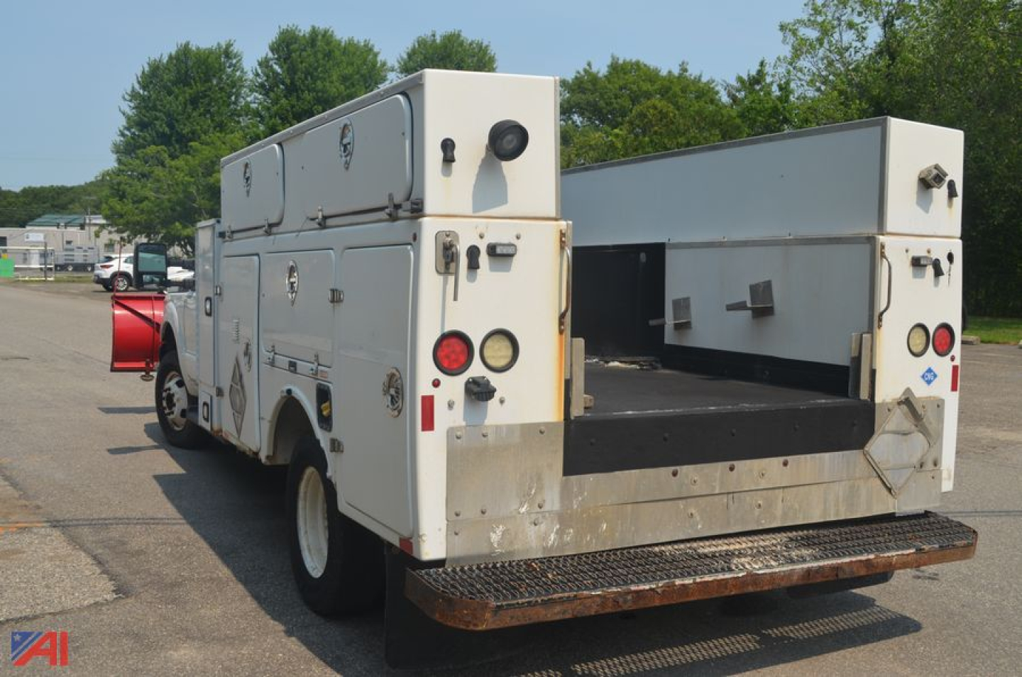 Ford F-350 utility body with rear ramp and plow equipment, white service truck with compartments and plow mount.